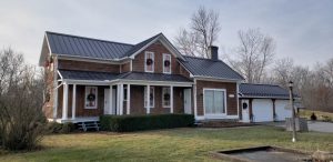 Brown house with black standing seam metal roof and white trim.