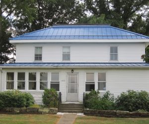 White two-story house with a blue standing seam metal roof.