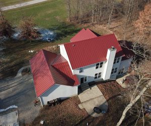 White house with a red standing seam metal roof.
