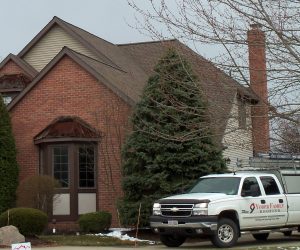 Brick home with Yoder Family Roofing truck parked in front.