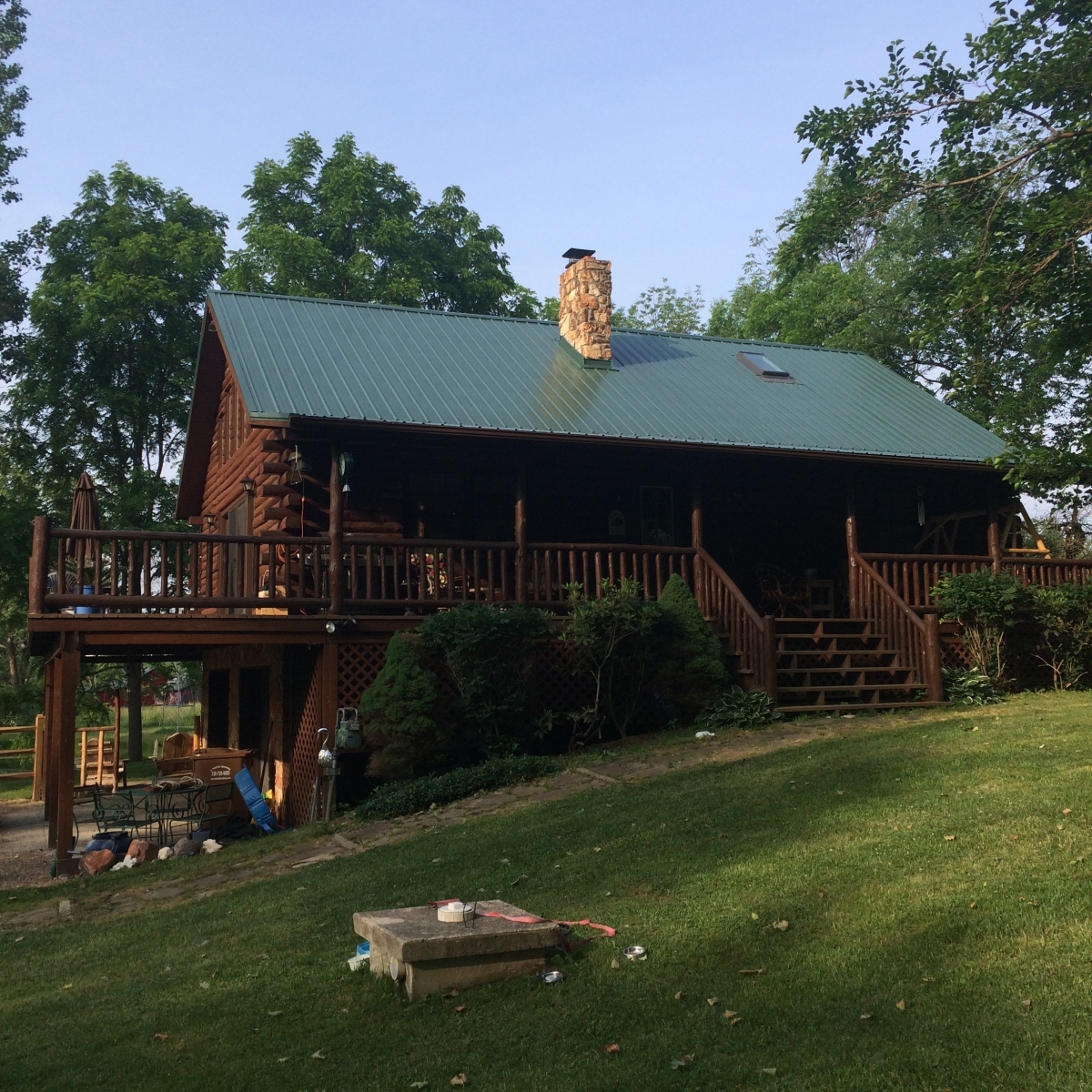 Red barn with standing seam metal roof and roofing truck parked outside.