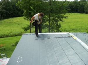 A crew member working on installing a new roof for a residential home